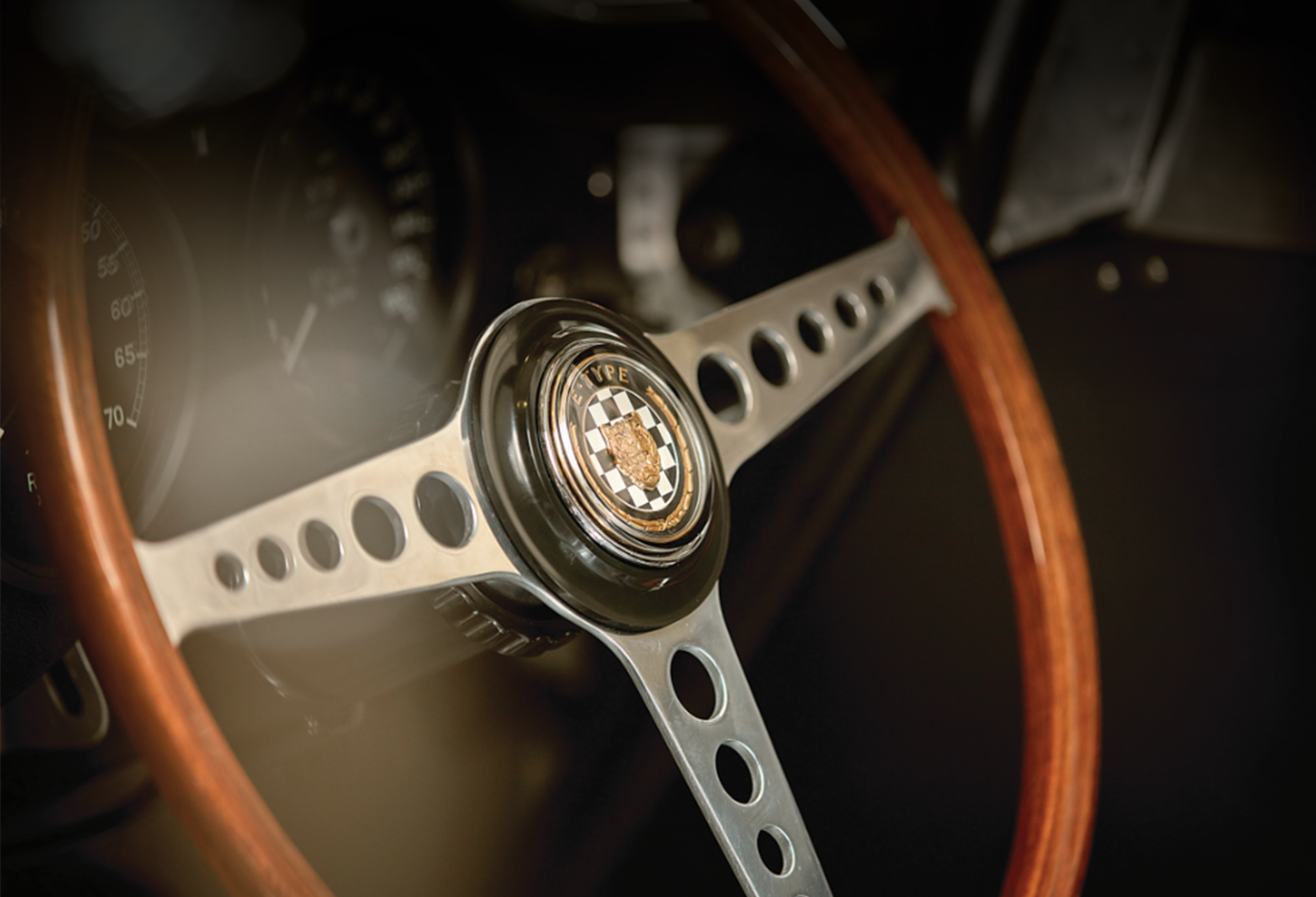 Classic car steering wheel with “E-TYPE” customised emblem.