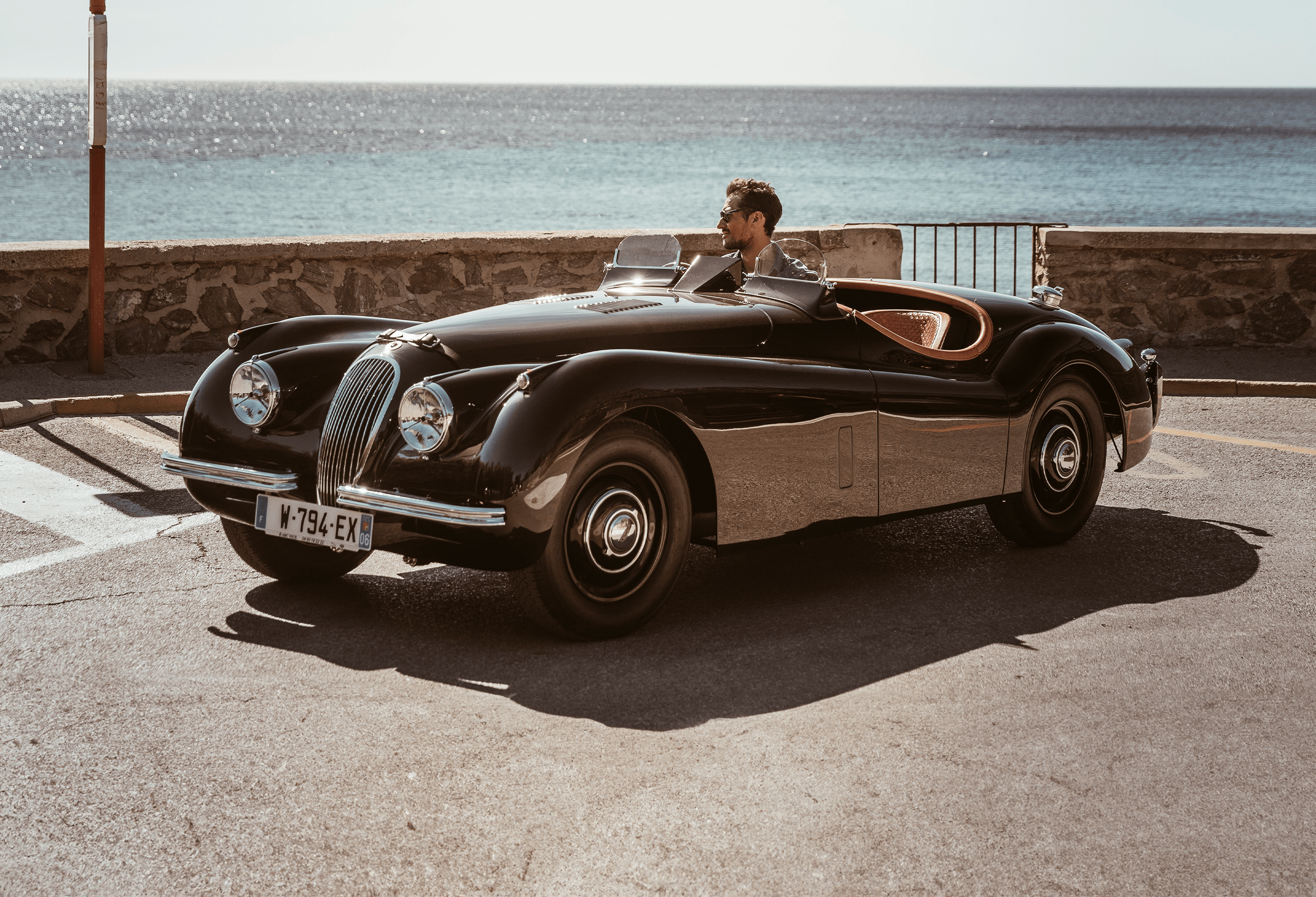 Classic black Jaguar convertible parked by the sea.