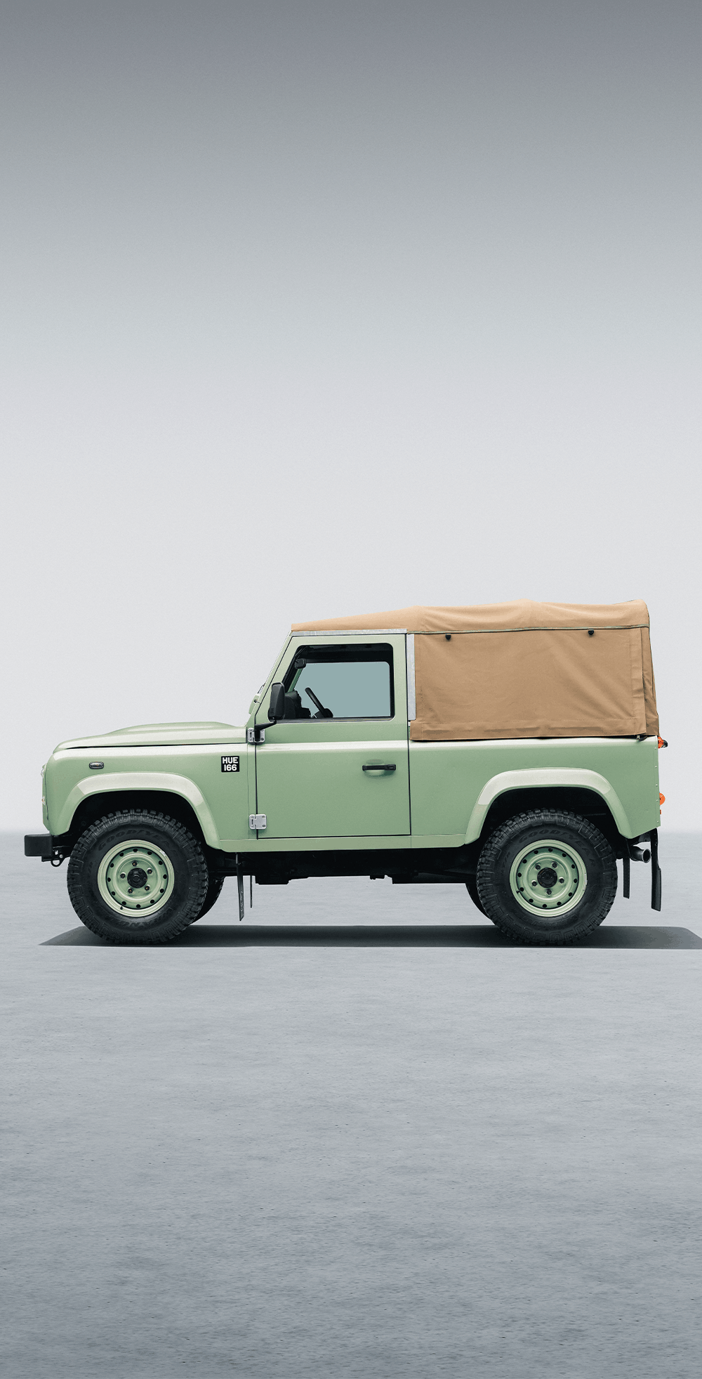 Jaguar E-Type and Land Rover Defenders displayed in a polished showroom.