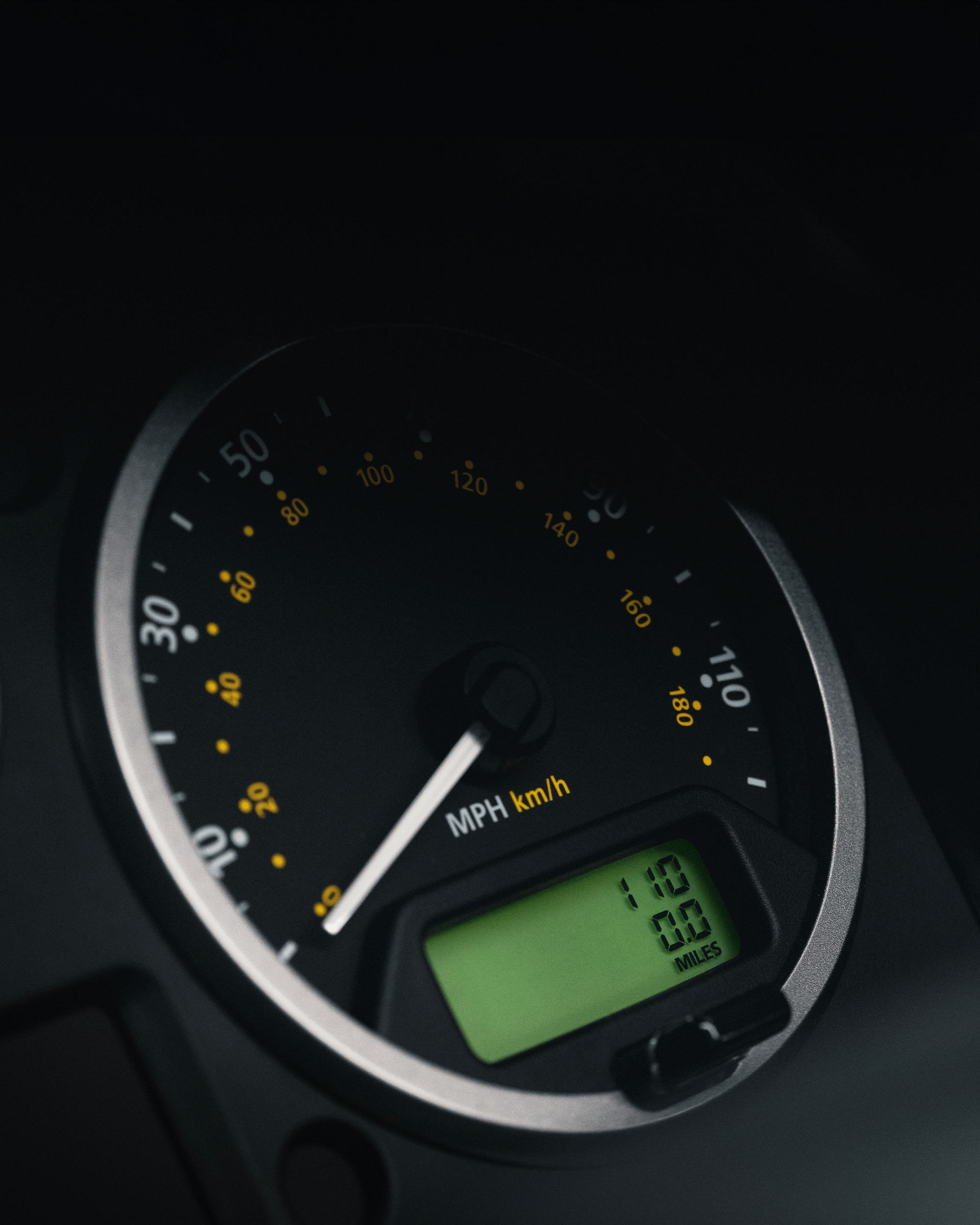 Three Land Rover Defender vehicles in a showroom, front view; nearest one is green with license plate 'HUE 166'.