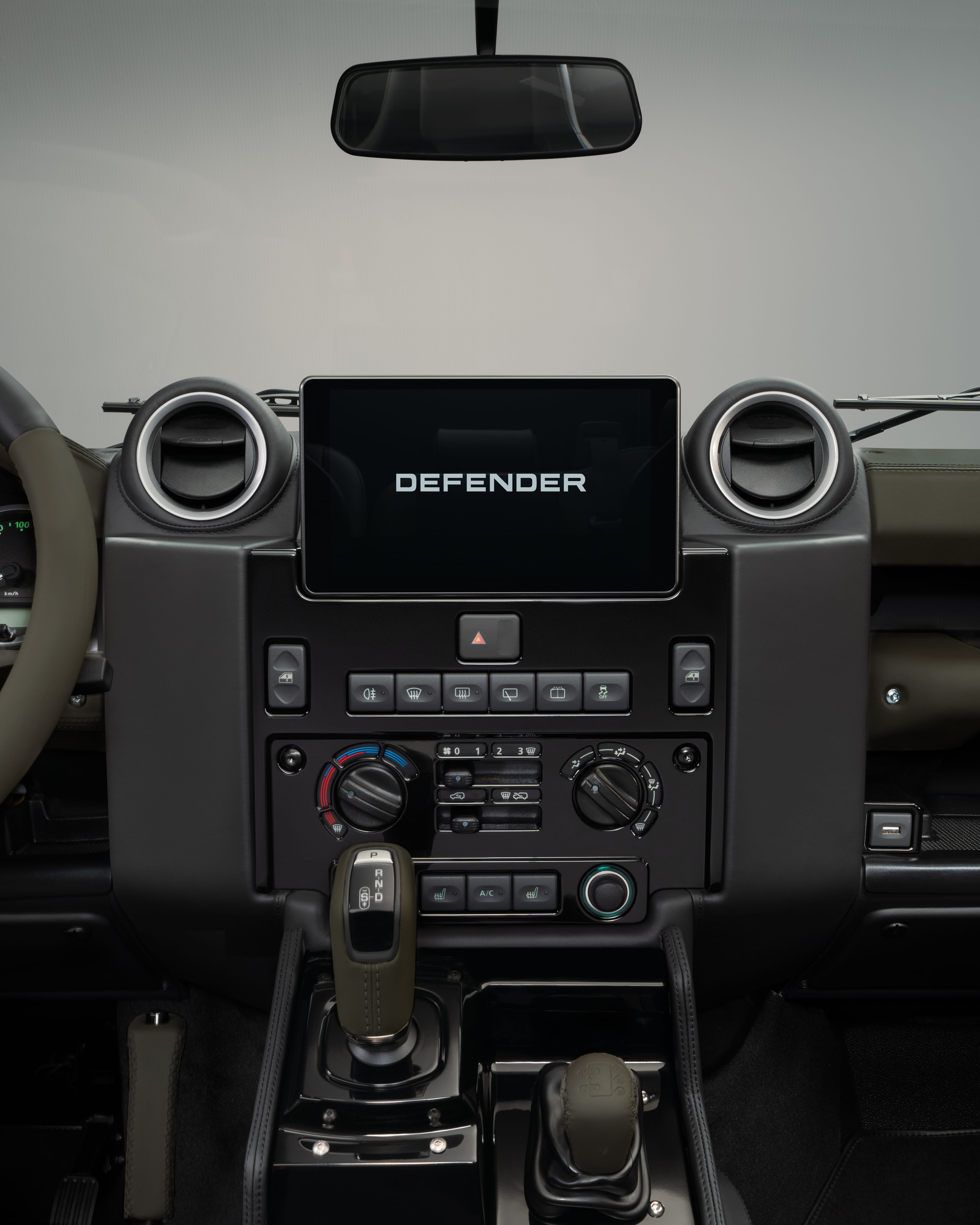 Front view of a black Defender with visible grille, headlights, and side mirror.