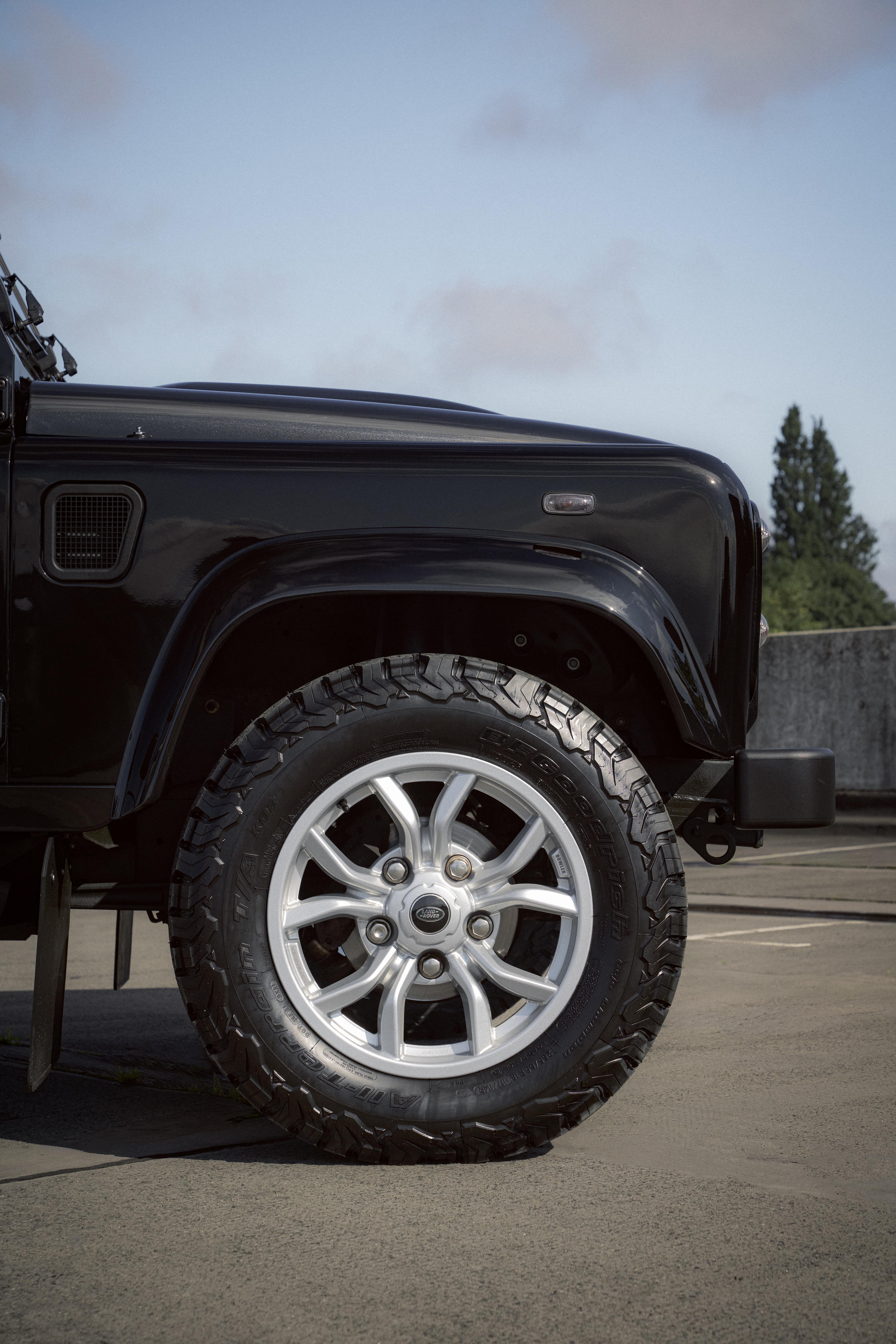 Front left wheel of a black Defender in an outdoor setting.