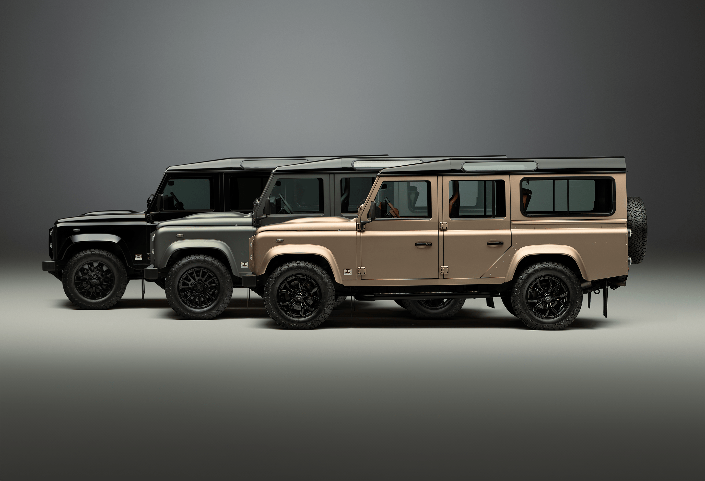 A red Defender V8 in the sand and grass.