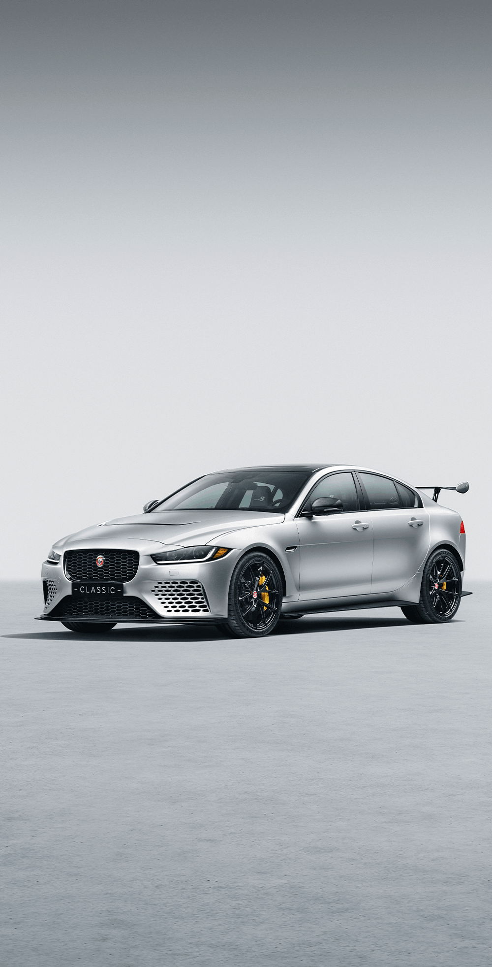 Jaguar E-Type and Land Rover Defenders displayed in a polished showroom.