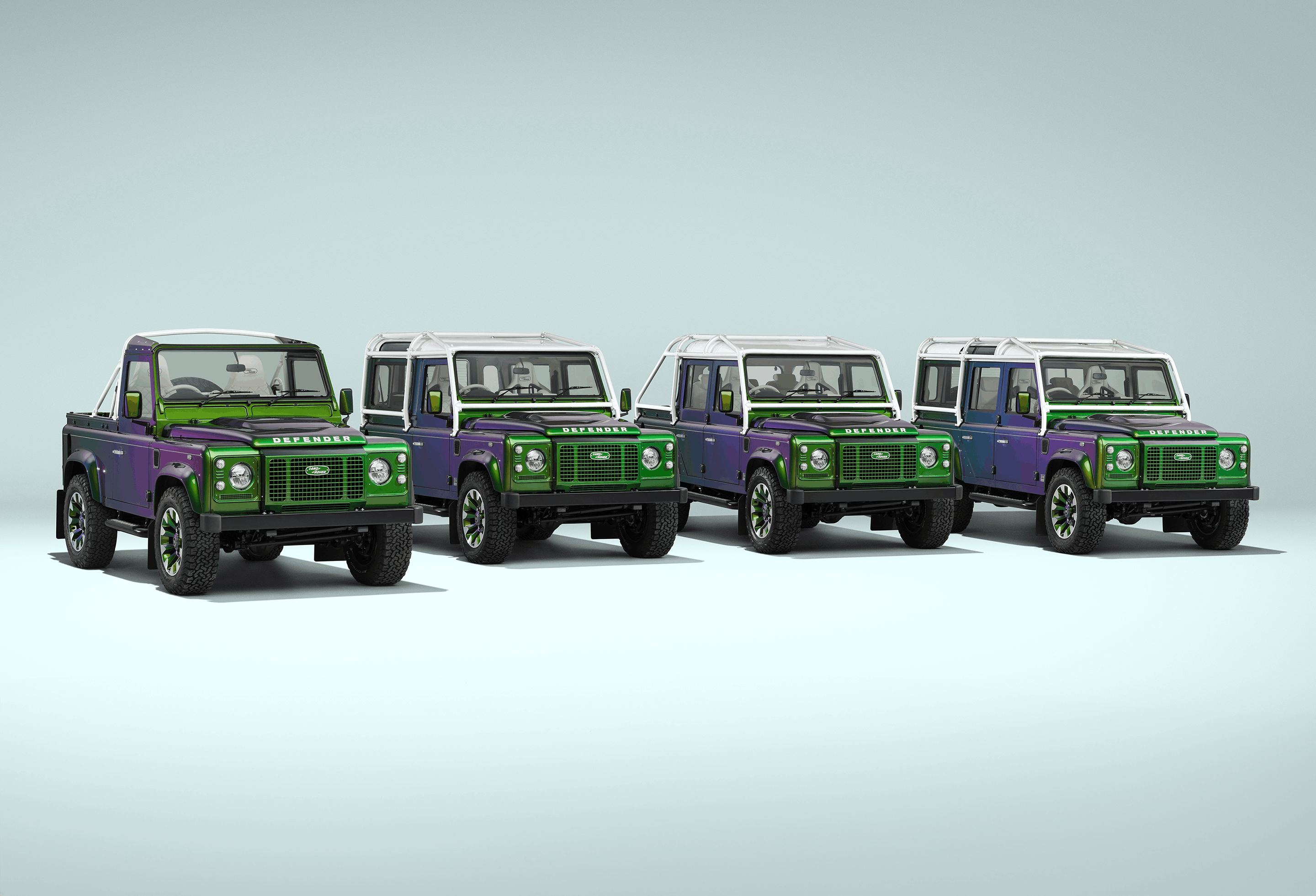 A red Defender V8 in the sand and grass.