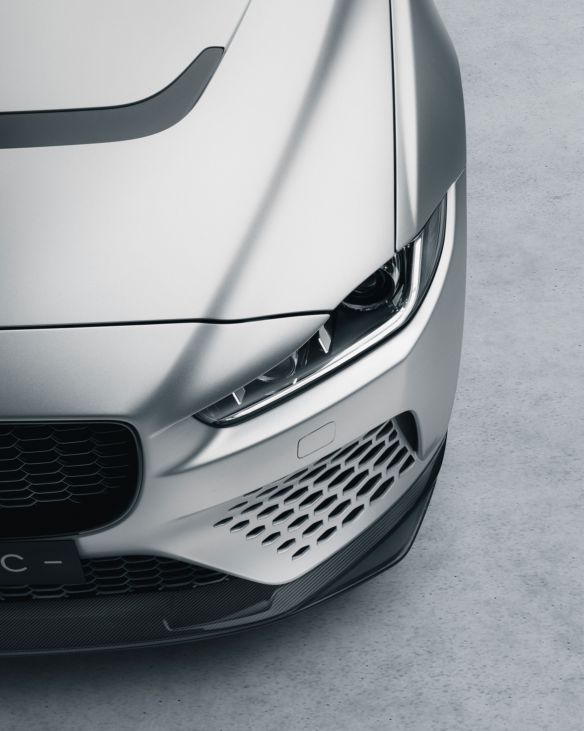 Three Land Rover Defender vehicles in a showroom, front view; nearest one is green with license plate 'HUE 166'.