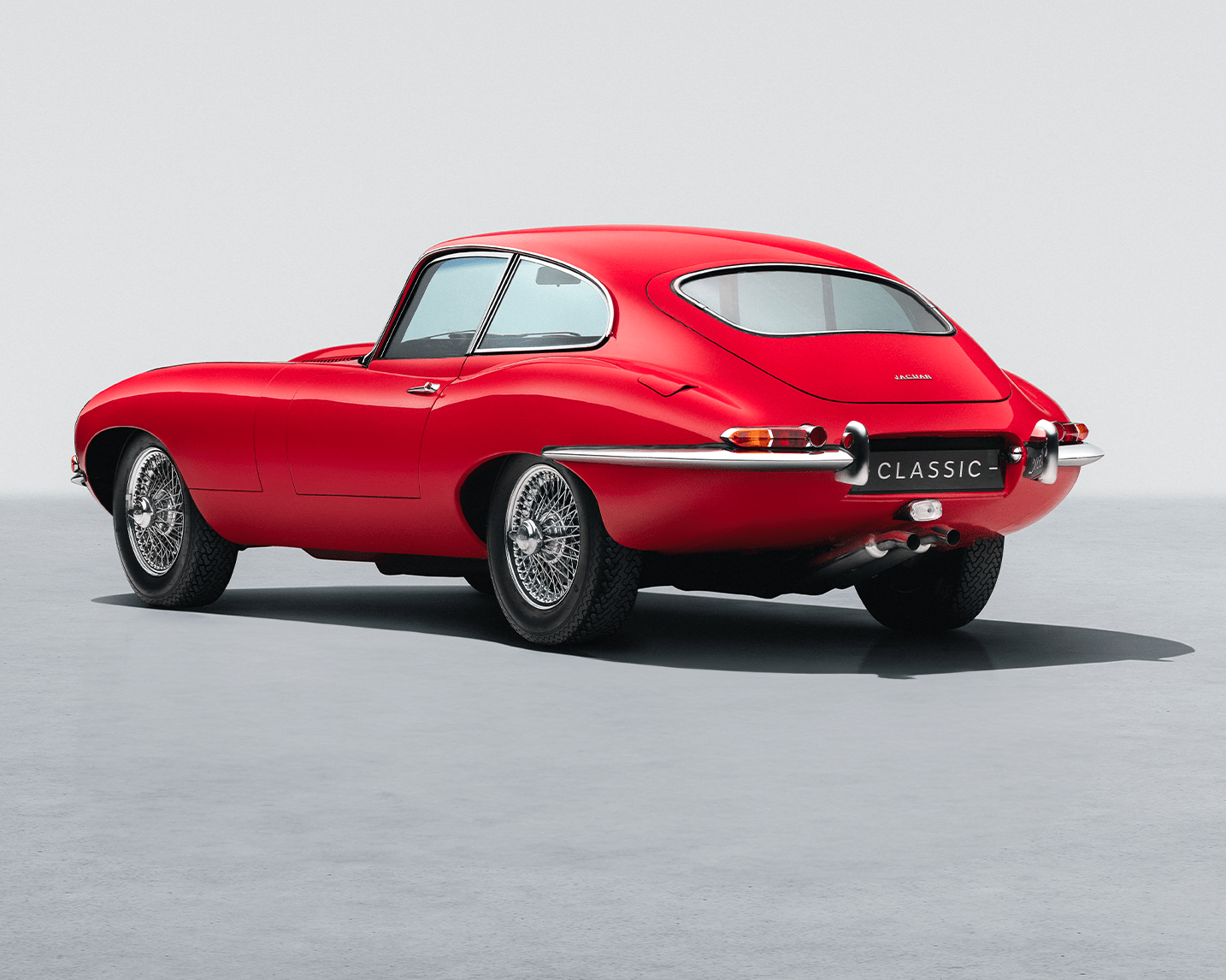 A dark green D-type driving on a track.