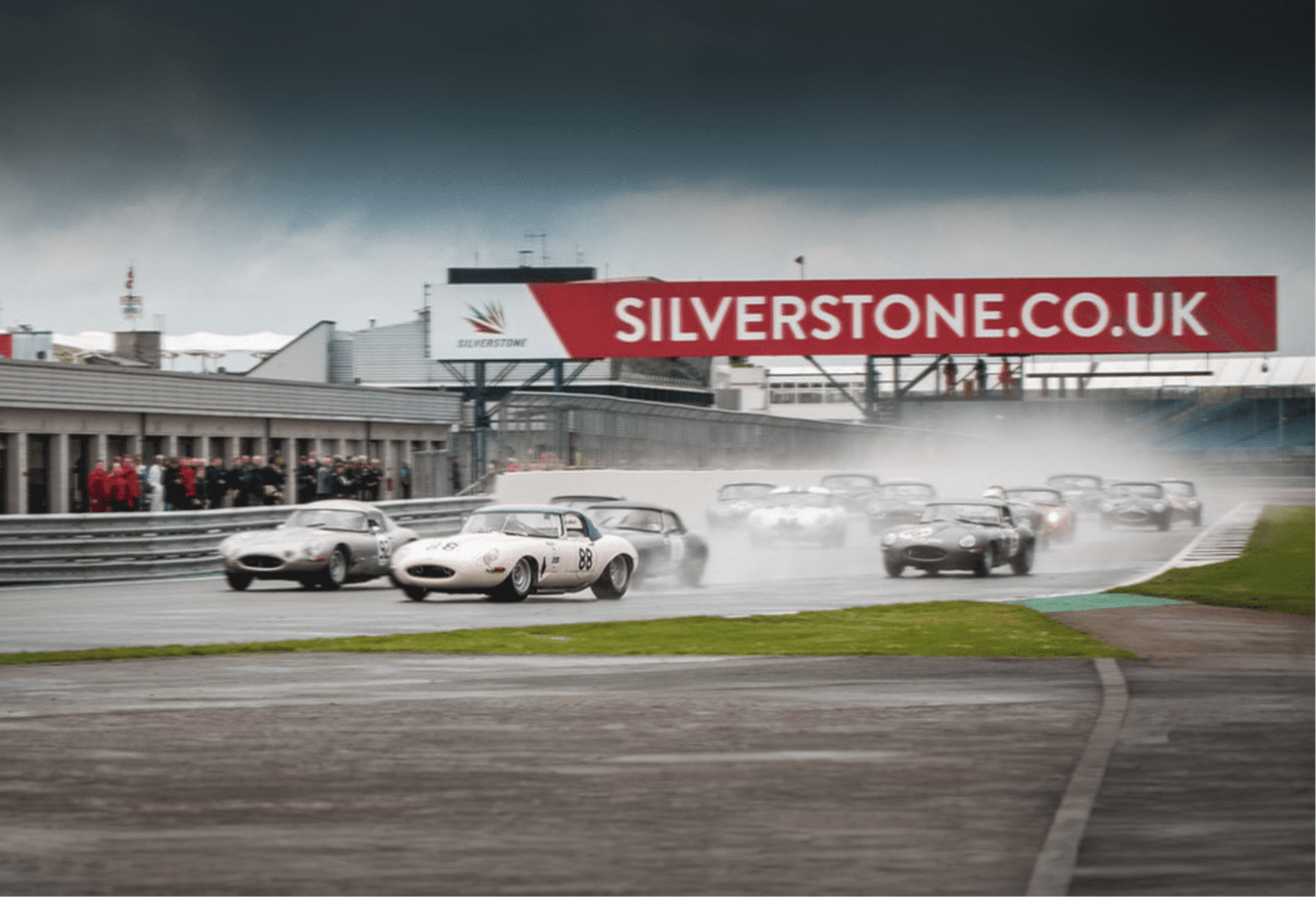 Classic race cars on wet track at Silverstone.