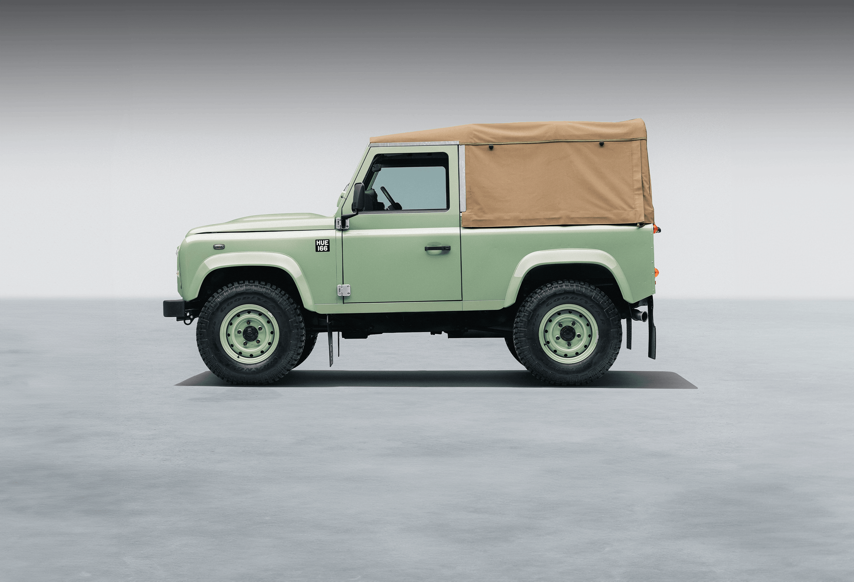 Jaguar E-Type and Land Rover Defenders displayed in a polished showroom.